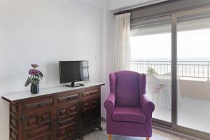 Playa de MiramarにあるApartamento Guardamar de la Saforのリビングルーム(紫色の椅子、テレビ付)