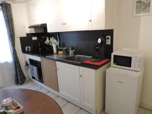 a small kitchen with a sink and a microwave at Auprès du Lavoir in Remigny +27 photos