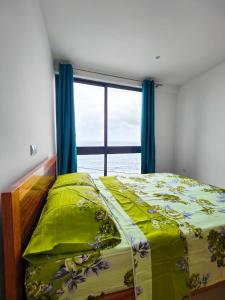 ein Bett in einem Zimmer mit Fenster und einer Tagesdecke in der Unterkunft Casa Nova in Ribeira Grande