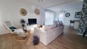 a living room with a white couch and a tv at Superbe Maison avec jardin in Bezannes-les-Reims