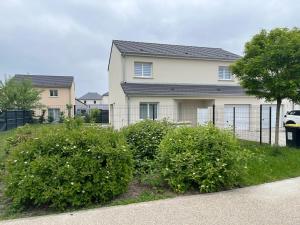 a house with bushes in front of a fence at Superbe Maison avec jardin in Bezannes-les-Reims