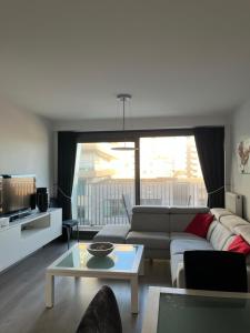 a living room with a couch and a table at JuLieze Apartment at Sea & Pool in Ostend