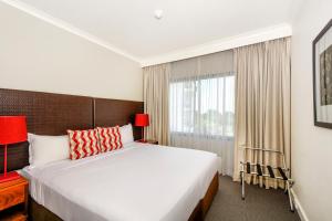 a bedroom with a large bed and a window at Mantra on The Esplanade in Darwin