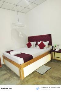 a bedroom with a large bed with red pillows at Almond Breeze Cottage in Udawalawe