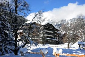 a building covered in snow in front of a mountain at Hotel Garni St. Hubertus in Madonna di Campiglio