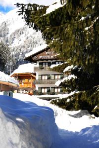 a hotel in the mountains with snow on the ground at Hotel Garni St. Hubertus in Madonna di Campiglio