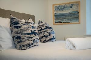 a bed with three blue and white pillows on it at River View Cottages in Annan