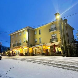 a large building on a street with snow on the ground at O Vicente in Loriga