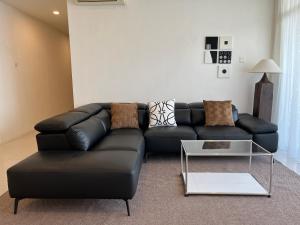 a black leather couch in a living room with a table at Leegarden Apartment-3BR in Sibu