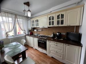 a kitchen with white cabinets and a table and a dining room at Apartament Centru in Cugir