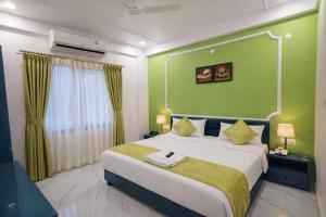 a bedroom with a large bed with a green wall at Hotel The Hood in Nagpur
