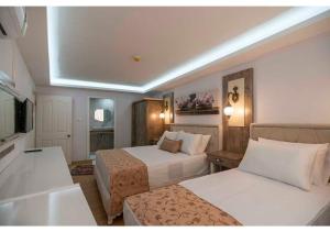 a hotel room with two beds and a television at Elit Lara Otel in Salihli