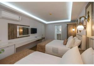 a hotel room with two beds and a television at Elit Lara Otel in Salihli