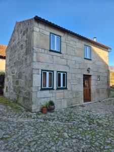 a small stone building with a door and windows at Casinha do Pátio in Nogueira do Cravo
