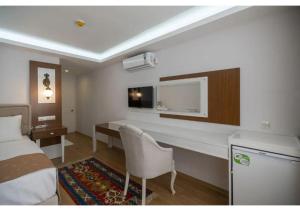 a hotel room with a bed and a desk and a bed and a room at Elit Lara Otel in Salihli +15 photos