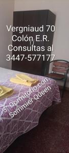 a bed with a purple comforter next to a chair at Vergniaud 70 in Colón