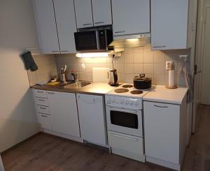 a kitchen with white cabinets and a stove top oven at Air conditioned Apartment in Espoo