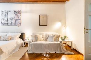 a white bedroom with two beds and two tables at Casa Vacanza Pablo Castello in Cagliari