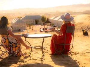 two women sitting at a table on the beach at Luxury Dune's Camp in Merzouga +24 photos