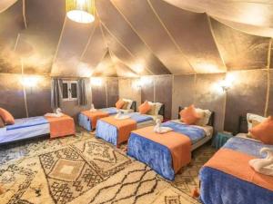 a group of four beds in a room at Luxury Dune's Camp in Merzouga