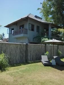 a house with a fence and two chairs and an umbrella at Ju'Blu Villa in Lovina