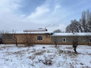a brick building in a field with snow on it at Adventure Guest House in Pokrovka