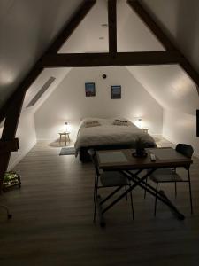a attic bedroom with a bed and a table at Ferme du grand treille in Haverskerque