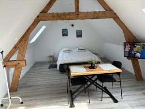 a attic bedroom with a bed and a table at Ferme du grand treille in Haverskerque