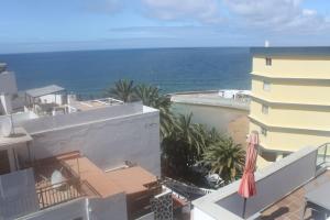 a view of the ocean from a building with an umbrella at Arguineguín sol y playa in Arguineguín