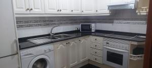 a kitchen with white cabinets and a sink and a dishwasher at Gáldar-Centro in Gáldar
