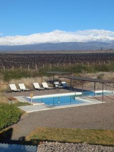 a swimming pool with lounge chairs and mountains in the background at Tupungato Divino in Tupungato