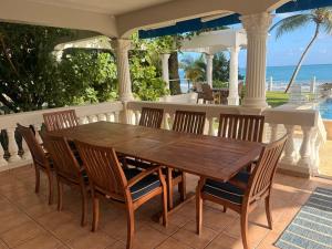 a wooden table and chairs on a porch with the ocean at Beachfront Luxury Bungalow Private Premium Pool in Fortuna