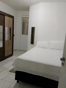 a white bedroom with a bed and a door at Kitnet mobiliado a minutos do Parque do Povo in Campina Grande