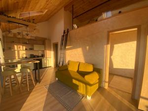 a living room with a yellow couch and a kitchen at Royal Hill-Queen Chalet -Bran, Mountain View and Hot Tub in Sohodol +23 photos