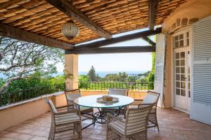a patio with a table and chairs on a balcony at Villa au calme jardin piscine proche mer et centre ville in Vallauris