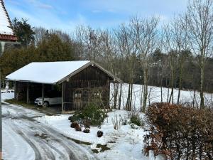 a barn covered in snow with a car parked next to it at Niedermaier Hof in Bad Birnbach +8 photos