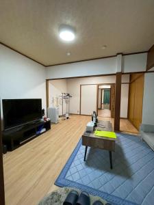 a living room with a flat screen tv and a table at Modern style old house in Nagoya