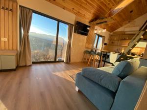 a living room with a couch and a large window at Royal Hill-Prince Chalet Bran- Mountain View and Hot Tub in Sohodol