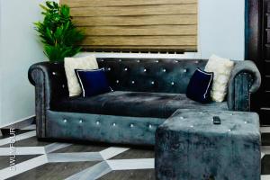 a leather couch with pillows and a table in a room at Caroline Cozy Apartment in Accra