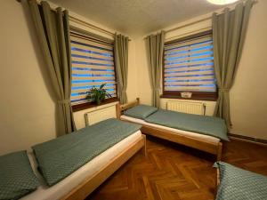 two beds in a room with two windows at Apartmán Renata in Rudník