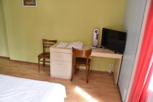 ein Zimmer mit einem Schreibtisch, auf dem ein Computer und ein Fernseher stehen in der Unterkunft Hôtel de l'ours in Vuiteboeuf