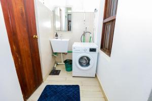 a small bathroom with a washing machine and a sink at CoastalCharms Zanzibar in Zanzibar City