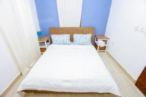 a bedroom with a large white bed with blue walls at CoastalCharms Zanzibar in Zanzibar City