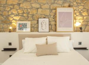 a bedroom with a white bed with pictures on a stone wall at Arbide House in Leioa
