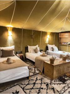 a bedroom with two beds in a tent at Aurum Dunes Luxury Camp in Merzouga