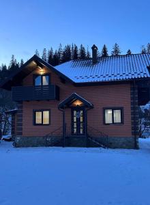 a house with snow on the ground in front of it at Brick House in Slavske