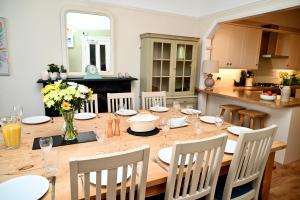 a dining room with a wooden table with chairs and a kitchen at Bay View, Sleeps 18, 7 Bedrooms, 7 Bathrooms, Seafront, Criccieth in Criccieth