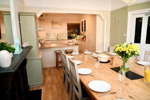 a dining room with a wooden table and a kitchen at Bay View, Sleeps 18, 7 Bedrooms, 7 Bathrooms, Seafront, Criccieth in Criccieth