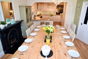 a long wooden table with white plates and flowers on it at Bay View, Sleeps 18, 7 Bedrooms, 7 Bathrooms, Seafront, Criccieth in Criccieth +144 photos