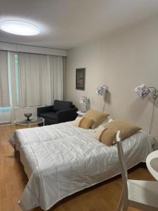 a bedroom with a large white bed and a chair at Kylpylä-hotelli 261 in Ikaalinen